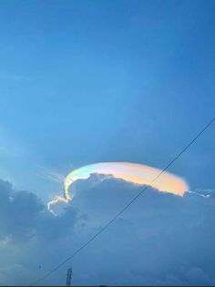 a rainbow colored cloud in the sky above power lines