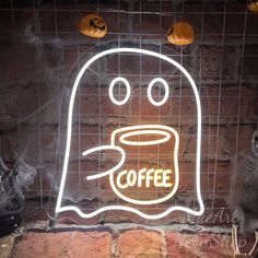 a neon sign that reads coffee with a ghost face on it and pumpkins hanging from the ceiling