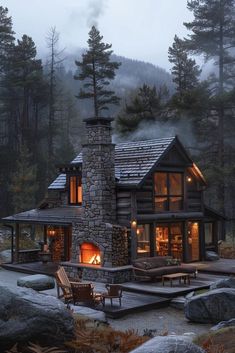 a log cabin is lit up at night in the woods with rocks and trees surrounding it