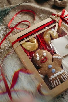 two gingerbreads in a gift box with red ribbon on the table next to it