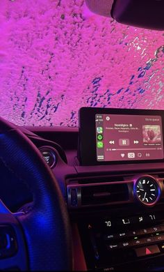 the dashboard of a car with an electronic device in it's center console and purple lighting