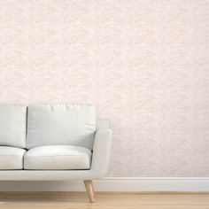 a white couch sitting in front of a pink wall