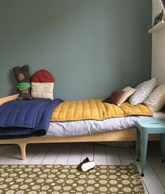 a bed with pillows and blankets on it in a room next to a blue wall