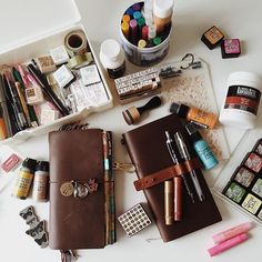 the contents of a travel bag laid out on a white table with pens and markers