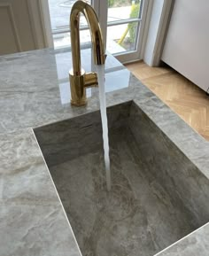 a faucet running out of a sink in a kitchen with marble counter tops