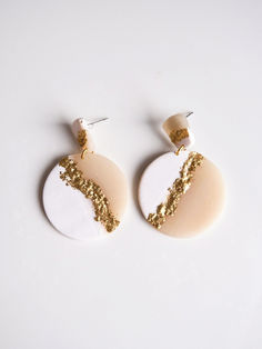 two white and gold earrings on a white surface