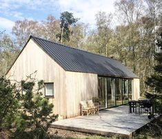 a small wooden cabin in the woods with a deck and table set up on it