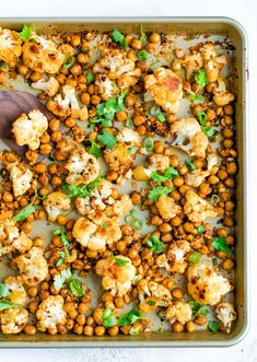 cauliflower and chickpeas in a baking dish with a wooden spoon