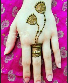 a woman's hand with henna and jewelry on top of her hands,