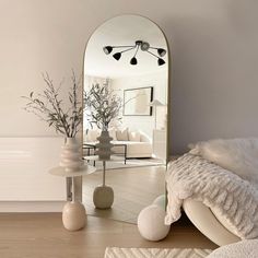 a mirror sitting on top of a wooden floor next to a vase filled with flowers