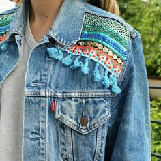 a woman wearing a jean jacket with colorful trims