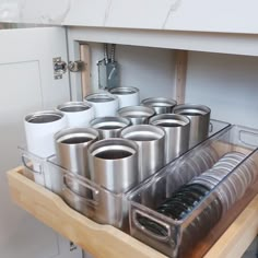 a drawer with many cups and pans in it