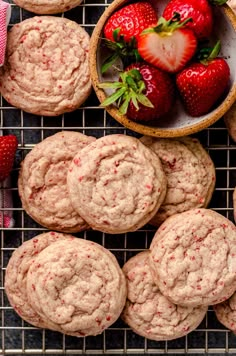 strawberry muffins on a cooling rack with fresh strawberries in the bowl next to them