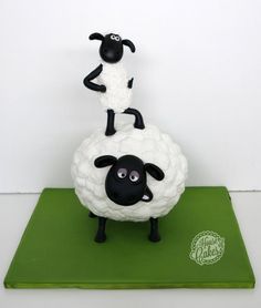 a black and white sheep standing on top of a green mat