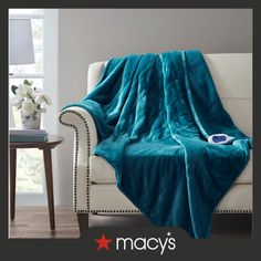 a couch covered in a teal blanket next to a table with flowers on it