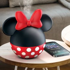 a minnie mouse speaker sitting on top of a table next to a cell phone and tablet