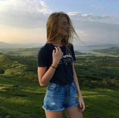 a woman standing on top of a lush green hillside