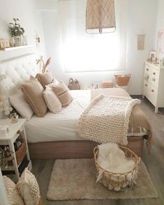 a bedroom with white walls and wooden floors, decorated in neutral colors including beiges and browns