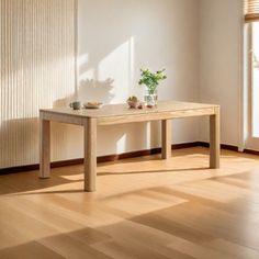 a wooden table sitting on top of a hard wood floor next to a window with blinds