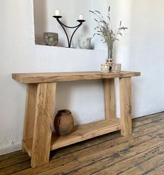 a wooden table sitting on top of a hard wood floor next to a white wall