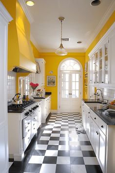 a kitchen with yellow walls and black and white checkered flooring on the tile