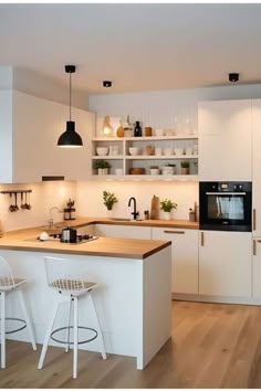 a kitchen with white cabinets and counter tops, two stools in front of the island