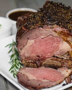 a large piece of meat sitting on top of a white plate next to some dipping sauce