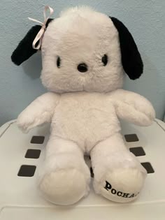 a white stuffed animal sitting on top of a scale with a black dog on it's head