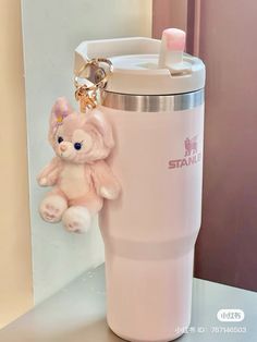 a pink teddy bear keychain hanging from the side of a coffee cup holder