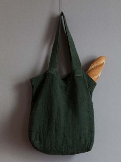 a green bag hanging on the wall next to a piece of bread with a wooden stick sticking out of it