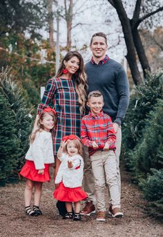 a family posing for a photo in front of christmas trees