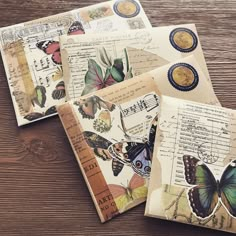 four envelopes with butterflies on them sitting on top of a wooden table next to each other