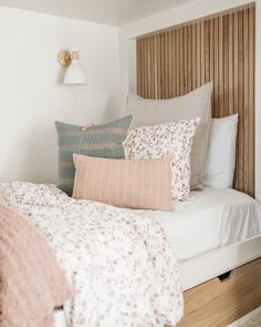 a bed with several pillows on top of it and a night stand next to it