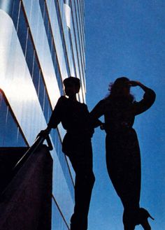 two women are standing in front of a tall building