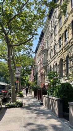 a street with cars parked on the side of it next to tall buildings and trees