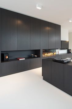 a kitchen with black cabinets and a fire place in the center, along with white flooring