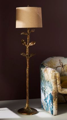 a lamp sitting next to a chair in a room with a purple wall behind it