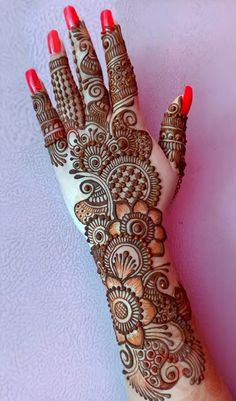 henna tattoo on the palm of a woman's hand with red nail polish