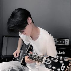 a young man is playing an electric guitar