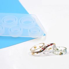 three rings sitting next to each other on top of a white table with blue background