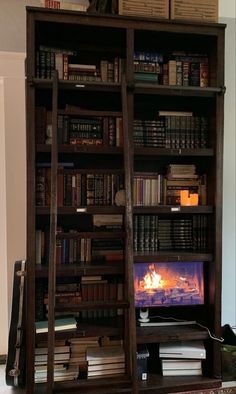 a bookshelf filled with lots of books next to a fire place