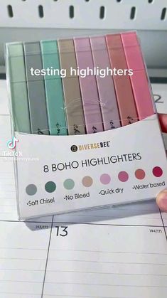 a person holding up a box with eight different colored highlighters in it's packaging