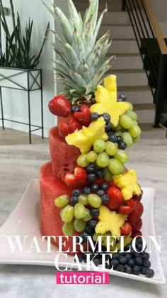 a pineapple and watermelon cake with fruit on top is displayed in front of stairs