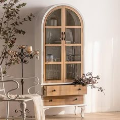 a white chair sitting next to a wooden cabinet with glass doors on it's sides