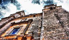 an old brick building with a blue window on the top and sky in the background