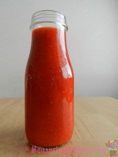 a jar filled with red sauce sitting on top of a wooden table