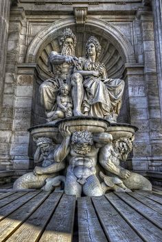 the statue is sitting on top of the wooden bench