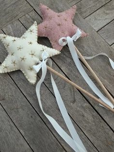 two stars on sticks are sitting on the ground next to some white ribbons and one has a pink star