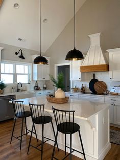 a kitchen with white cabinets and black bar stools in front of an island counter