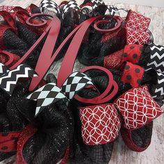 the monogrammed mesh wreath is decorated with black and red ribbons, polka dots, and letters